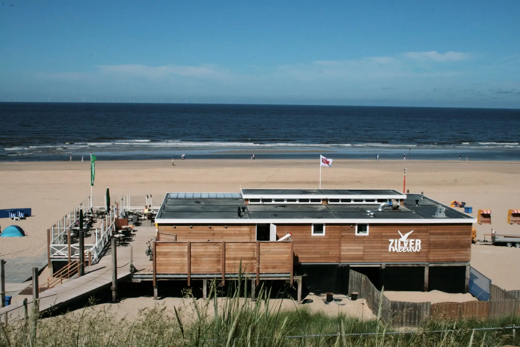 Zicht vanaf het duin op strandpaviljoen De Zilvermeeuw, de zee op de achtergrond