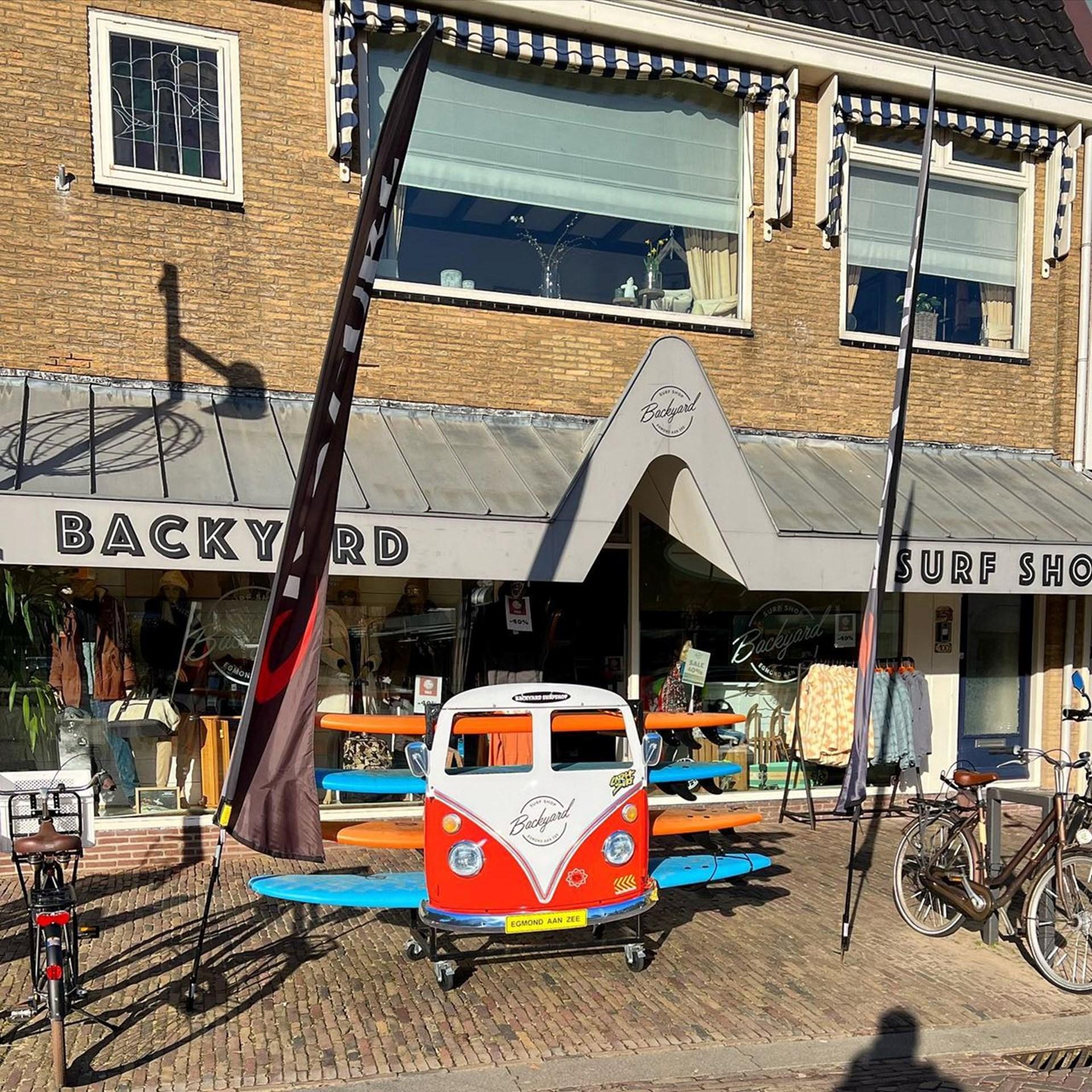 Buitenkant van Backyard Surf Shop met volkswagen met surfplanken