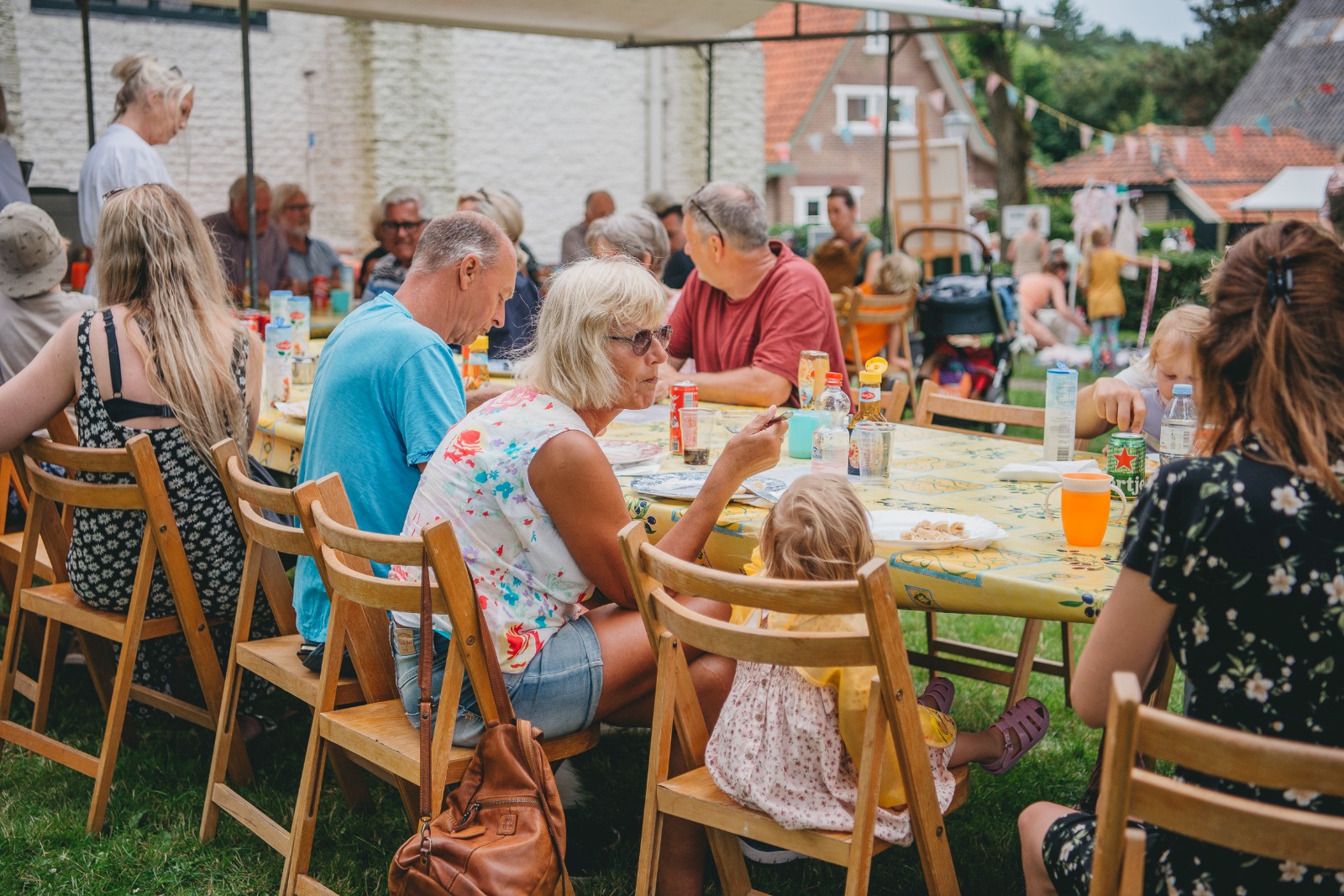 Lange tafel waaraan mensen en kinderen zitten om wat te eten en drinken op de zomermarkt