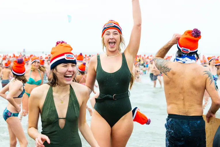 Vriendinnen rennen lachend de zee uit tijdens de nieuwjaarsduik.