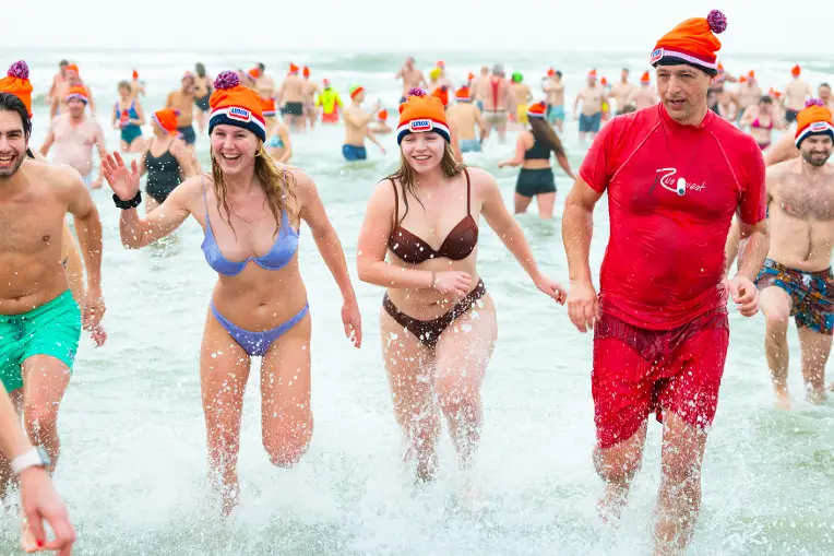 Vriendinnen rennen lachend de zee uit tijdens de nieuwjaarsduik.