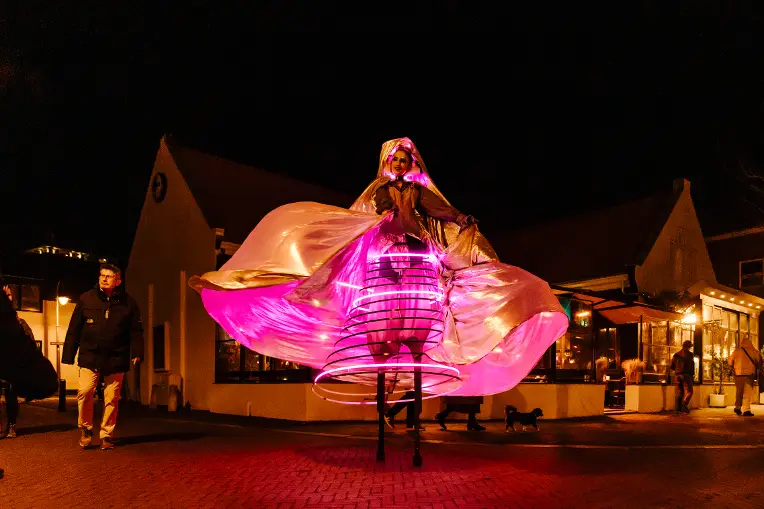 Vrouw op stelten met een verlichte jurk