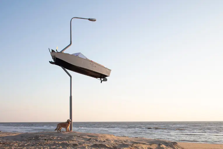 Kunst van een boot in een latarenpaal met de zee op de achtergrond.