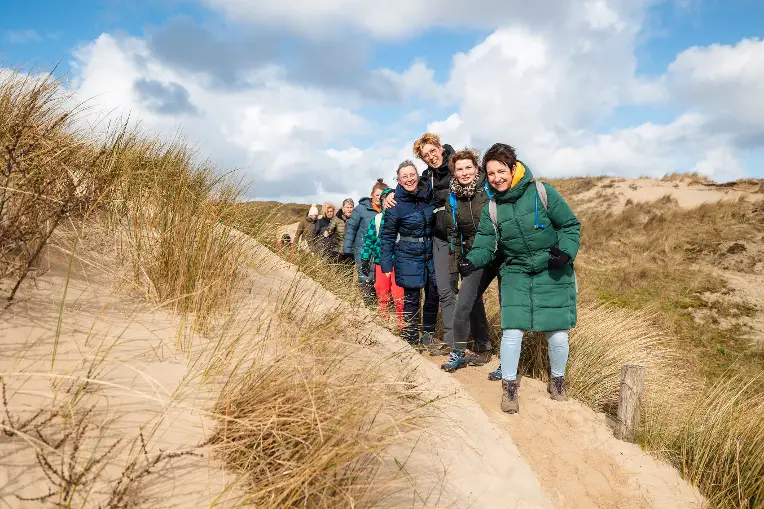 Lachende mensen lopen door de duinen tijdens de 30 van Zandvoort.